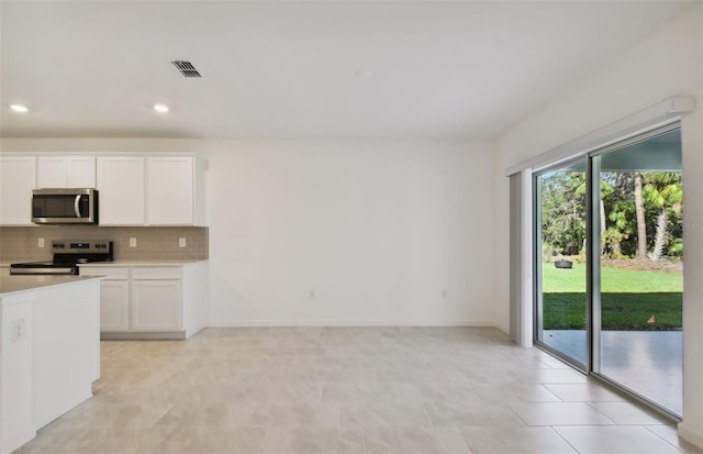 kitchen featuring white cabinets, light tile patterned floors, appliances with stainless steel finishes, and tasteful backsplash