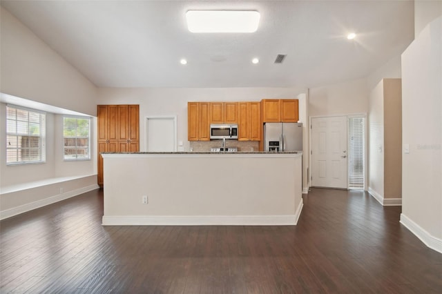 kitchen with stainless steel appliances, a kitchen island with sink, stone counters, dark hardwood / wood-style floors, and lofted ceiling