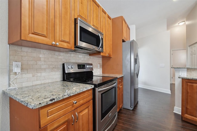 kitchen featuring tasteful backsplash, light stone counters, dark wood-type flooring, and appliances with stainless steel finishes