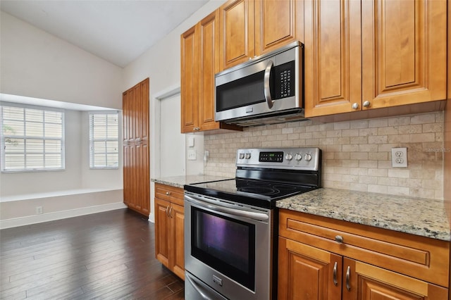 kitchen featuring light stone counters, dark hardwood / wood-style flooring, stainless steel appliances, and tasteful backsplash