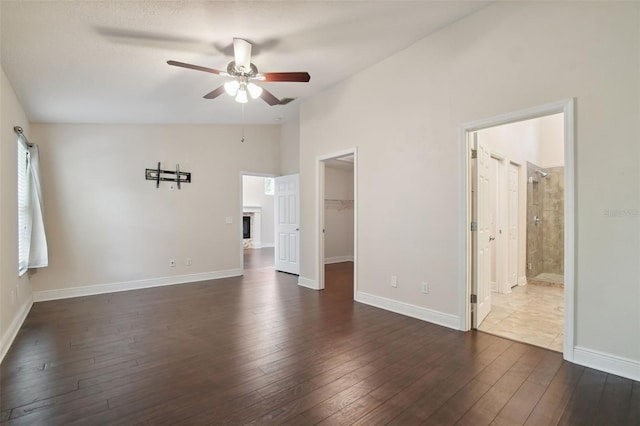 interior space with dark hardwood / wood-style flooring, a walk in closet, ensuite bathroom, ceiling fan, and a closet