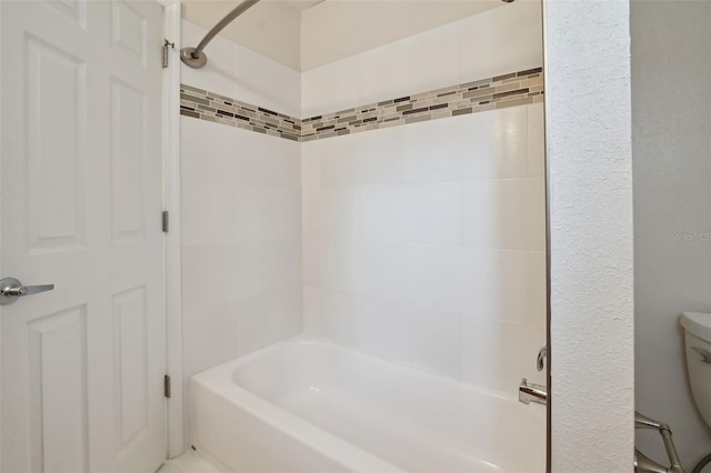 bathroom featuring tiled shower / bath combo and toilet