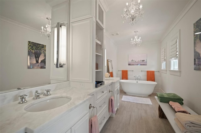 bathroom with a bathing tub, ornamental molding, a chandelier, vanity, and hardwood / wood-style flooring