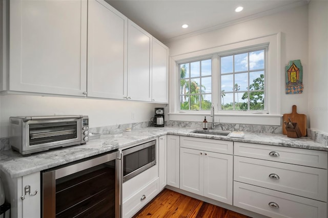 kitchen featuring light hardwood / wood-style floors, white cabinetry, sink, and beverage cooler