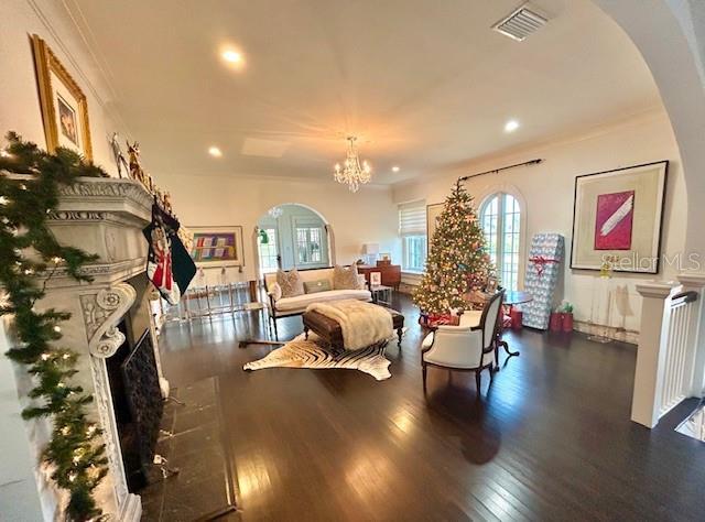 living room featuring dark hardwood / wood-style floors, crown molding, and an inviting chandelier