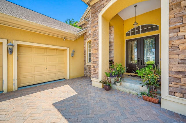 view of exterior entry featuring a garage and french doors