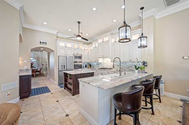1227 Toscano Dr, Trinity, FL 34655 - kitchen with stainless steel appliances, ornamental molding, arched walkways, a ceiling fan, and tasteful backsplash