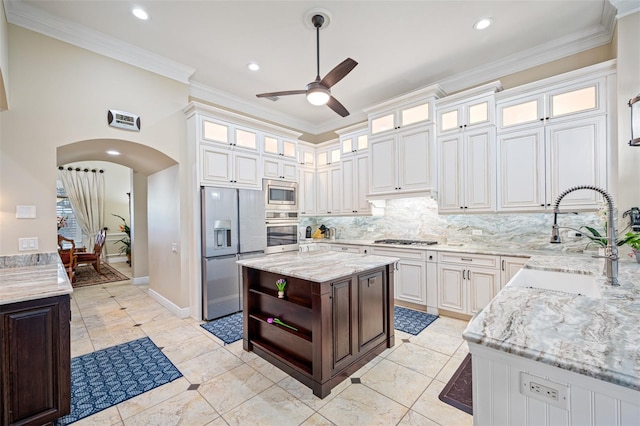 1227 Toscano Dr, Trinity, FL 34655 - kitchen with stainless steel appliances, arched walkways, ceiling fan, a sink, and decorative backsplash