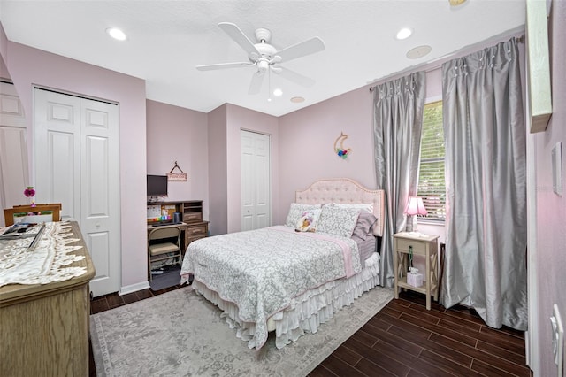 bedroom featuring ceiling fan, dark hardwood / wood-style flooring, and two closets