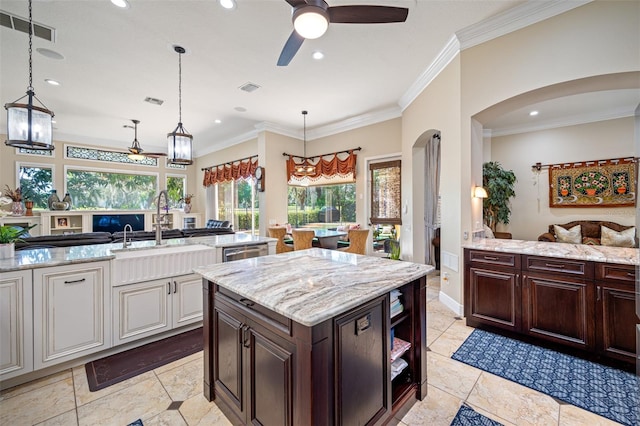 kitchen with ceiling fan, dark brown cabinets, decorative light fixtures, and ornamental molding