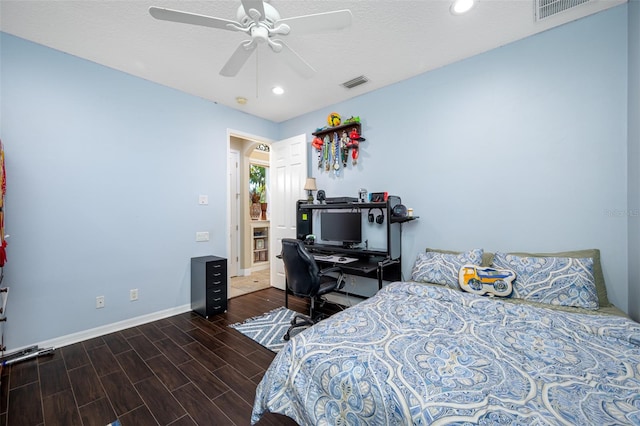 bedroom with a textured ceiling, dark hardwood / wood-style floors, and ceiling fan