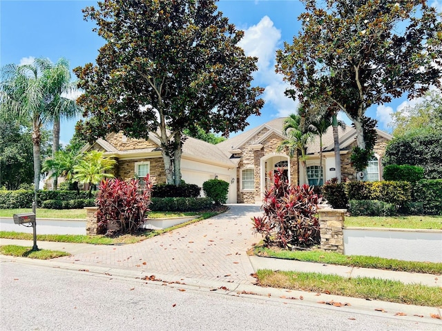 1227 Toscano Dr, Trinity, FL 34655 - view of property hidden behind natural elements featuring stone siding, an attached garage, and decorative driveway