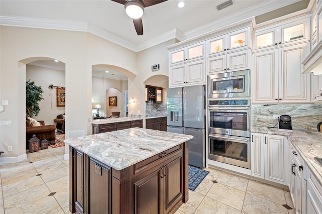 1227 Toscano Dr, Trinity, FL 34655 - kitchen featuring appliances with stainless steel finishes, ceiling fan, backsplash, light stone counters, and ornamental molding
