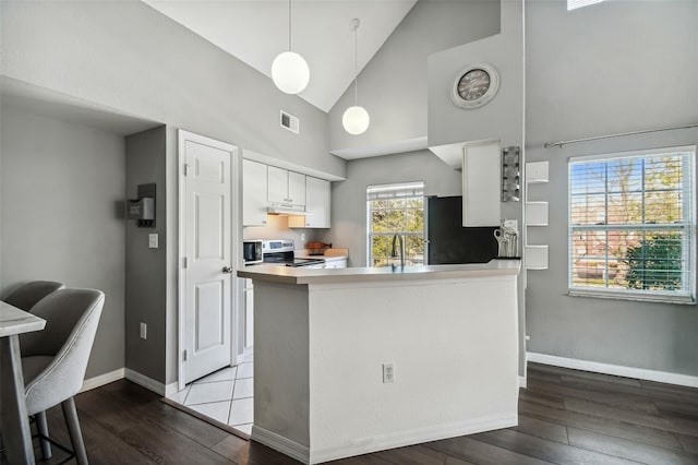 kitchen featuring kitchen peninsula, electric stove, black refrigerator, high vaulted ceiling, and white cabinets