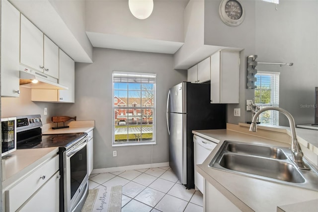 kitchen with stainless steel electric stove, sink, white cabinets, and light tile floors