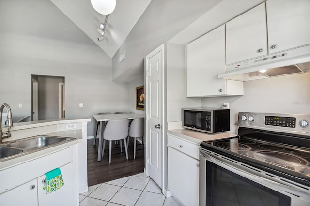 kitchen with rail lighting, stainless steel appliances, white cabinetry, and light tile floors