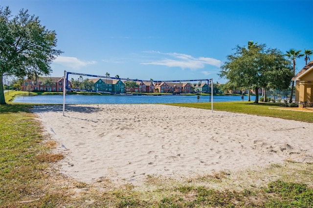 view of home's community featuring volleyball court, a water view, and a yard