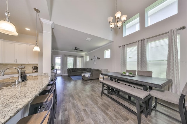 dining room with a wealth of natural light, dark hardwood / wood-style flooring, ceiling fan with notable chandelier, and ornamental molding