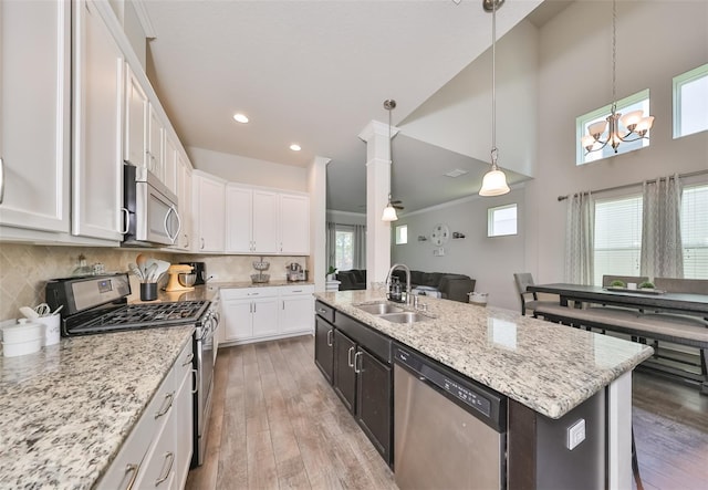 kitchen featuring white cabinets, sink, hanging light fixtures, an island with sink, and stainless steel appliances