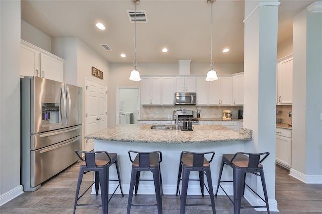 kitchen with white cabinetry, separate washer and dryer, stainless steel appliances, and hanging light fixtures