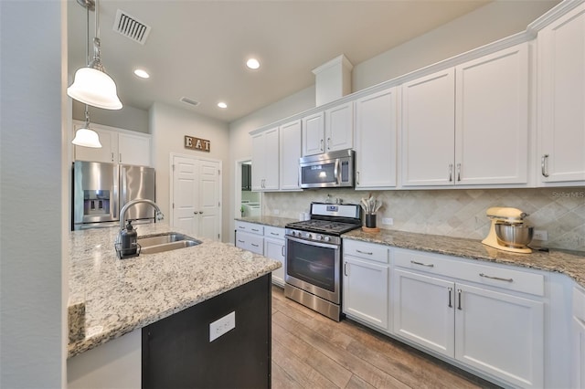 kitchen with sink, stainless steel appliances, backsplash, pendant lighting, and white cabinets