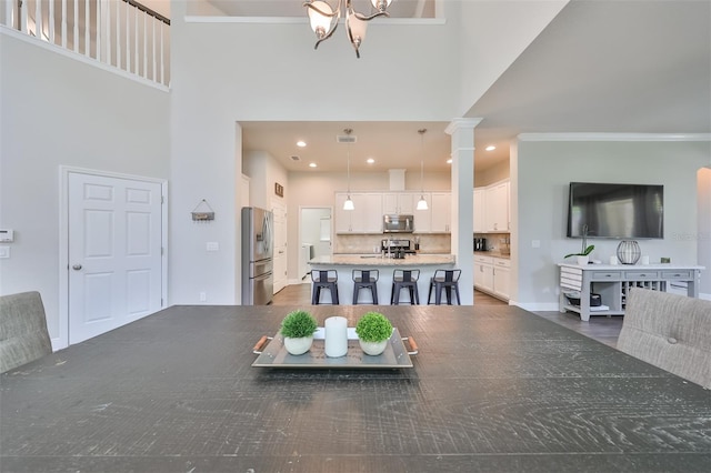 dining space featuring a chandelier, a high ceiling, ornamental molding, and sink