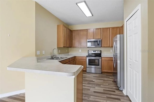 kitchen featuring kitchen peninsula, sink, stainless steel appliances, and light wood-type flooring