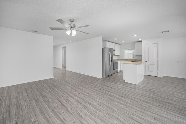 unfurnished living room with light hardwood / wood-style flooring, a textured ceiling, and ceiling fan