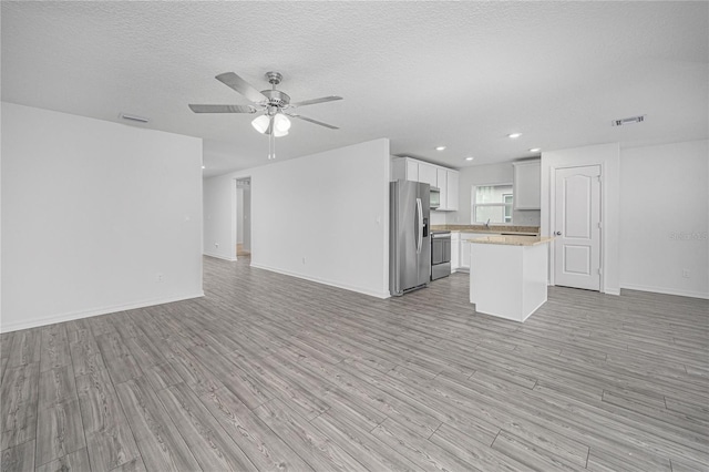 unfurnished living room with visible vents, baseboards, a ceiling fan, and light wood-style flooring