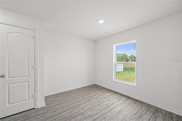 unfurnished room featuring light wood-type flooring, recessed lighting, baseboards, and a textured ceiling