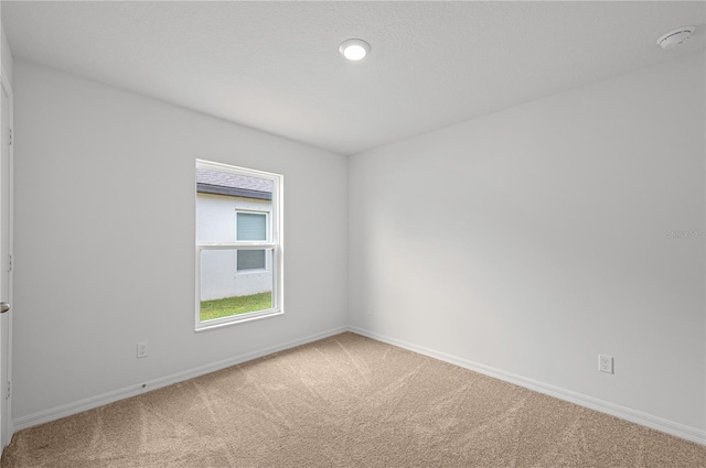 spare room with baseboards and carpet floors