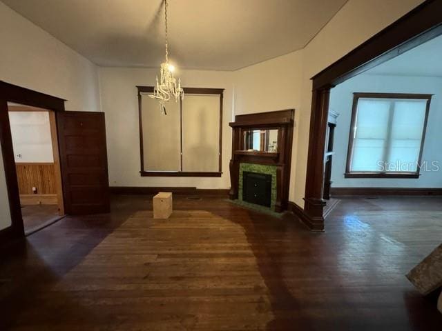 unfurnished living room with a notable chandelier and dark hardwood / wood-style floors