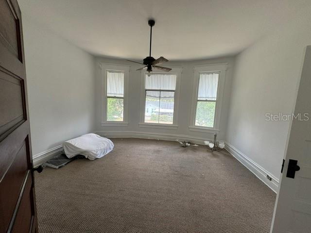 interior space with dark colored carpet and ceiling fan