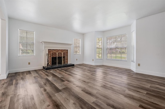 unfurnished living room featuring wood finished floors, plenty of natural light, a fireplace, and baseboards