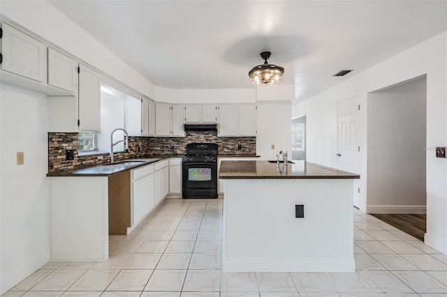 kitchen featuring gas stove, visible vents, a sink, decorative backsplash, and under cabinet range hood