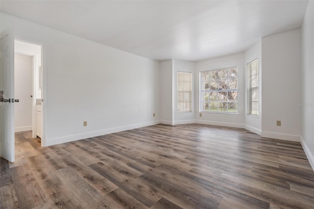 unfurnished room with baseboards and dark wood-type flooring