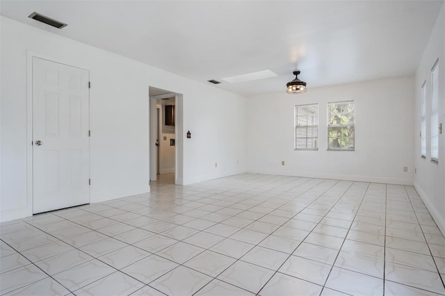 unfurnished room with light tile patterned flooring, visible vents, a skylight, and baseboards