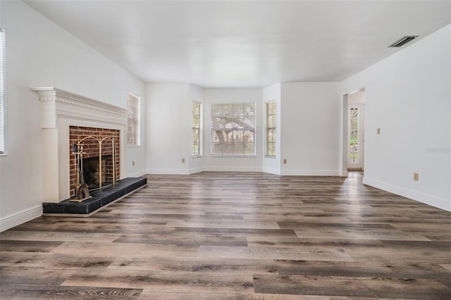 unfurnished living room with visible vents, a fireplace, baseboards, and wood finished floors