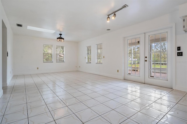 unfurnished room featuring visible vents, french doors, a skylight, light tile patterned floors, and baseboards