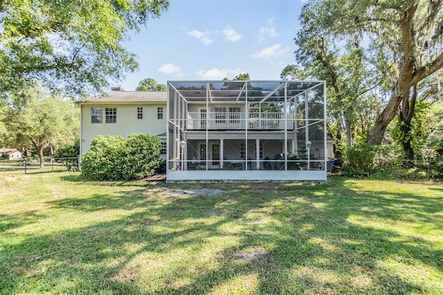 rear view of property with glass enclosure, a yard, and fence