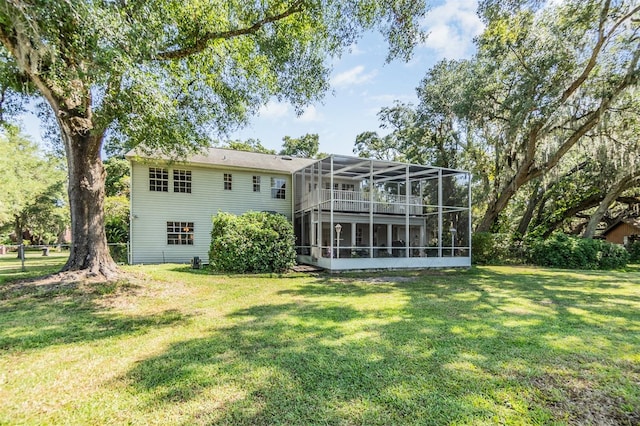 rear view of house featuring a lawn and a sunroom