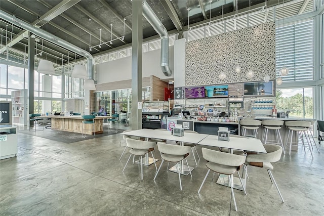 dining area featuring plenty of natural light, concrete flooring, and a high ceiling