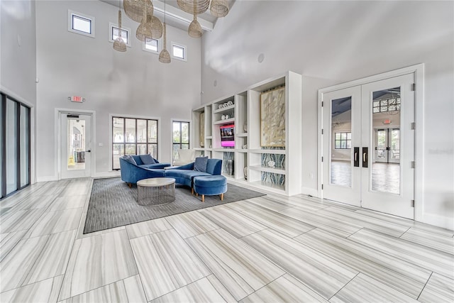 living room featuring built in shelves, french doors, and a high ceiling