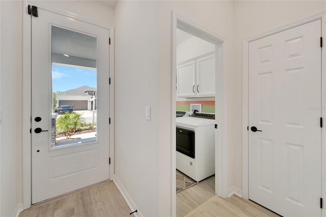 laundry area with light hardwood / wood-style flooring, cabinets, and washer / dryer