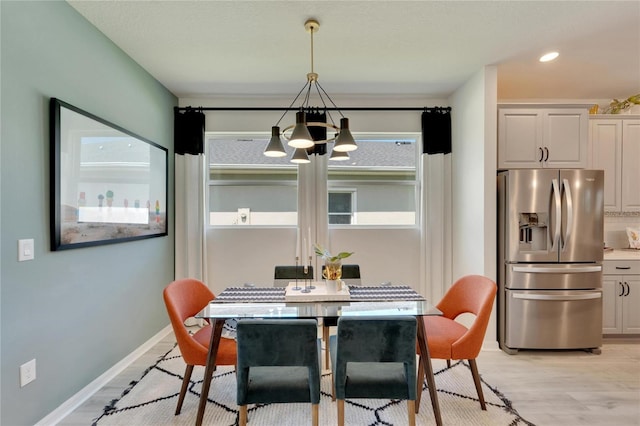 dining space with light hardwood / wood-style floors and a notable chandelier