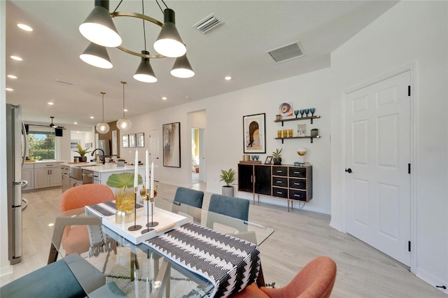 dining space featuring a chandelier, sink, and light hardwood / wood-style floors