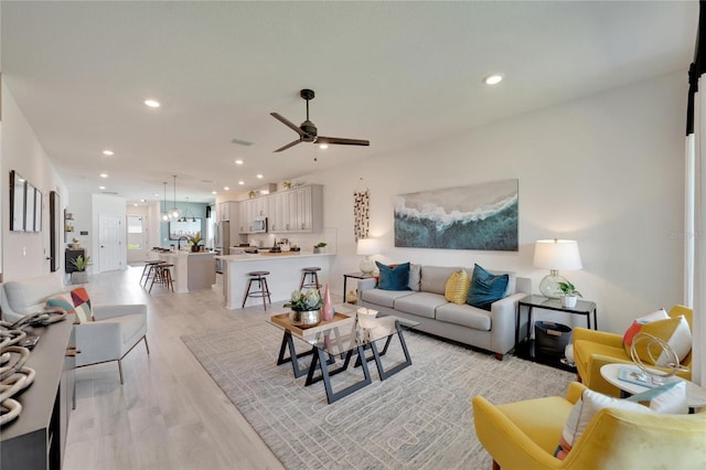 living room with ceiling fan and light hardwood / wood-style flooring