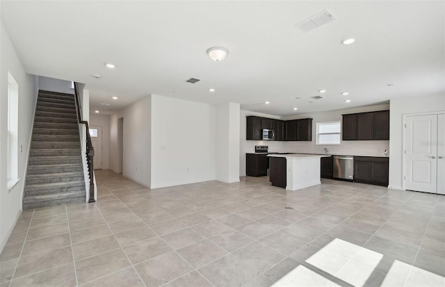 kitchen featuring dark brown cabinets, a center island, light tile patterned floors, and appliances with stainless steel finishes