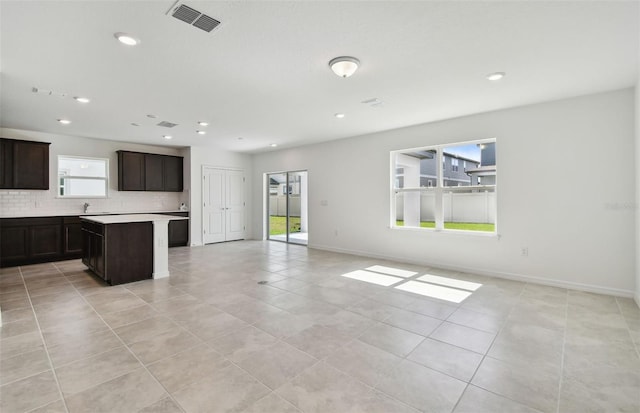 kitchen with decorative backsplash, a center island, light tile patterned floors, and dark brown cabinets