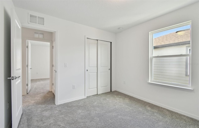 unfurnished bedroom with light carpet and a closet